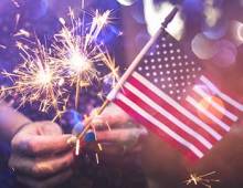 Girl holding an American flag and sparklers on the 4th of July